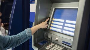 Pessoa fazendo retirada da poupança no caixa eletrônico.