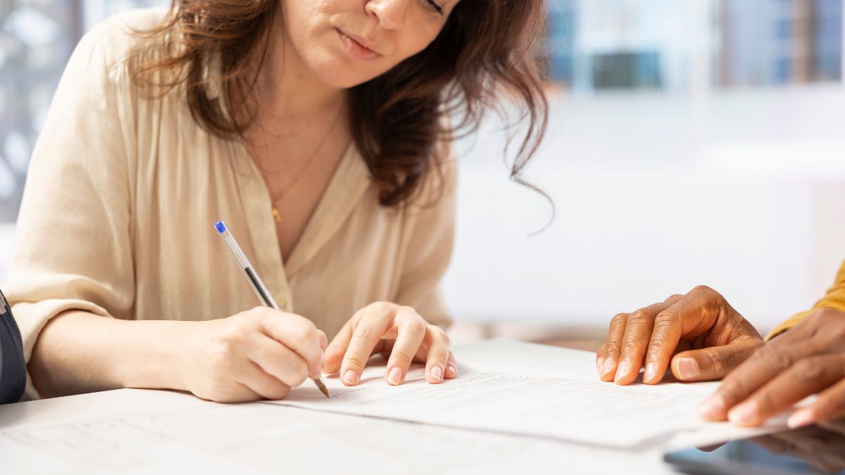 Mulher branca assinado documento, representando a contratação de seguro de vida no Brasil.