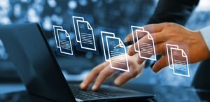 A imagem mostra uma pessoa digitando em um notebook, acima dele aparecem ícones de arquivos tecnológicos, como se fossem assinaturas digitais.