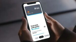 Pessoa segurando um smartphone exibindo o aplicativo do Banco Pan no 4T24, mostrando saldo disponível no cartão de crédito.