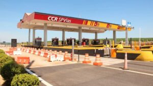 Praça de pedágio da CCR SPVias em rodovia brasileira, com cabines de cobrança e sinalização de segurança. Infraestrutura de concessão rodoviária.