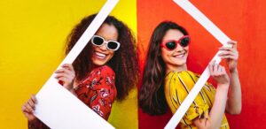 A imagem mostra duas meninas, com roupas coloridas e óculos coloridos, segurando uma moldura de polaroid, mostrando como o mercado de co-design no Brasil está crescendo.