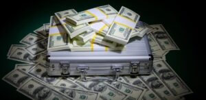 A imagem mostra uma maleta e várias notas de dólar em volta, simbolizando a cotação do dólar.