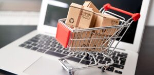 A descrição mostra um carrinho de supermercado cheio de caixas de compras em cima de um notebook, representando o crescimento do e-commerce no Brasil.