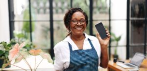 A imagem mostra uma mulher empreendedora segurando um celular para representar o desemprego no Brasil. e o empreendedorismo como alternativa.