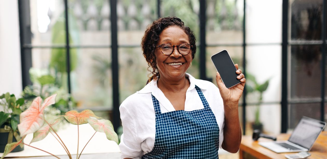 A imagem mostra uma mulher empreendedora segurando um celular para representar o desemprego no Brasil. e o empreendedorismo como alternativa.