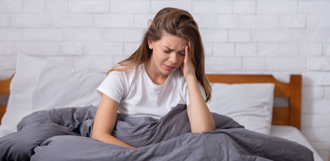 A imagem mostra uma mulher sentada na cama sem dormir, alavancando a economia do sono.