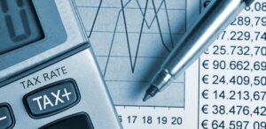 A imagem mostra uma calculadora, uma caneta e ao fundo um papel com gráficos desenhados para representar o equity crowdfunding.