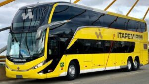 Ônibus de dois andares do Grupo Itapemirim, pintado de amarelo e preto, circulando sobre uma ponte. Veículo moderno com a marca da empresa.