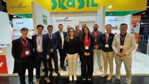 Equipe da M. Dias Branco reunida no stand da ISM 2025, em frente à estrutura com identidade visual do Brasil, destacando sua participação no evento."