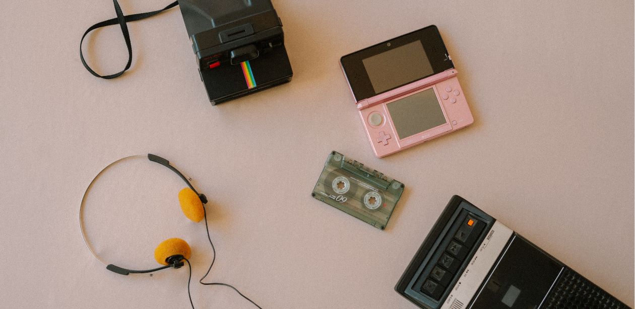 A imagem mostra elementos dos anos 80, 90 e 2000, como câmeras, fones de ouvido, fita cassete e outros, remetendo ao marketing de nostalgia.