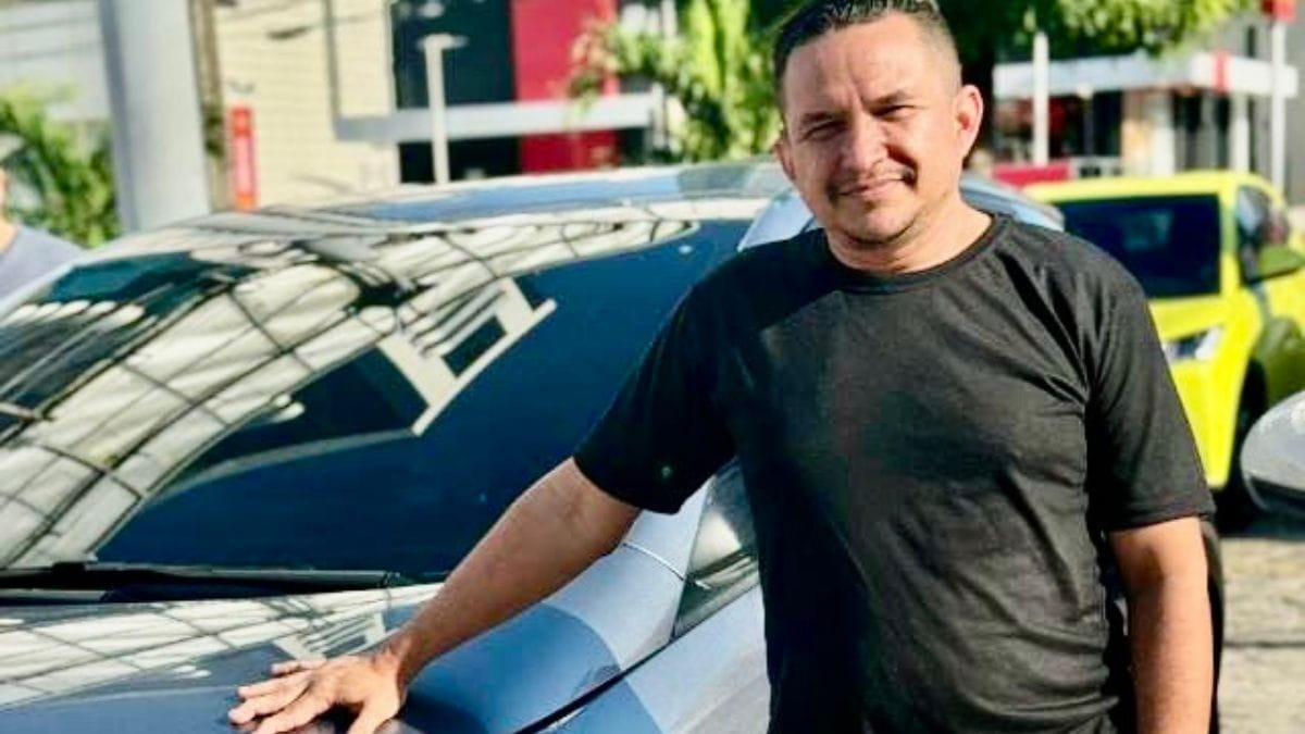 Motorista Adriano Leite da Costa ao lado de seu carro elétrico, destacando a economia e os benefícios dos carros elétricos para motoristas de aplicativo.