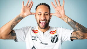 Neymar sorrindo e fazendo careta com a língua para fora, vestindo a camisa do Santos. Especula-se sua possível compra do clube.