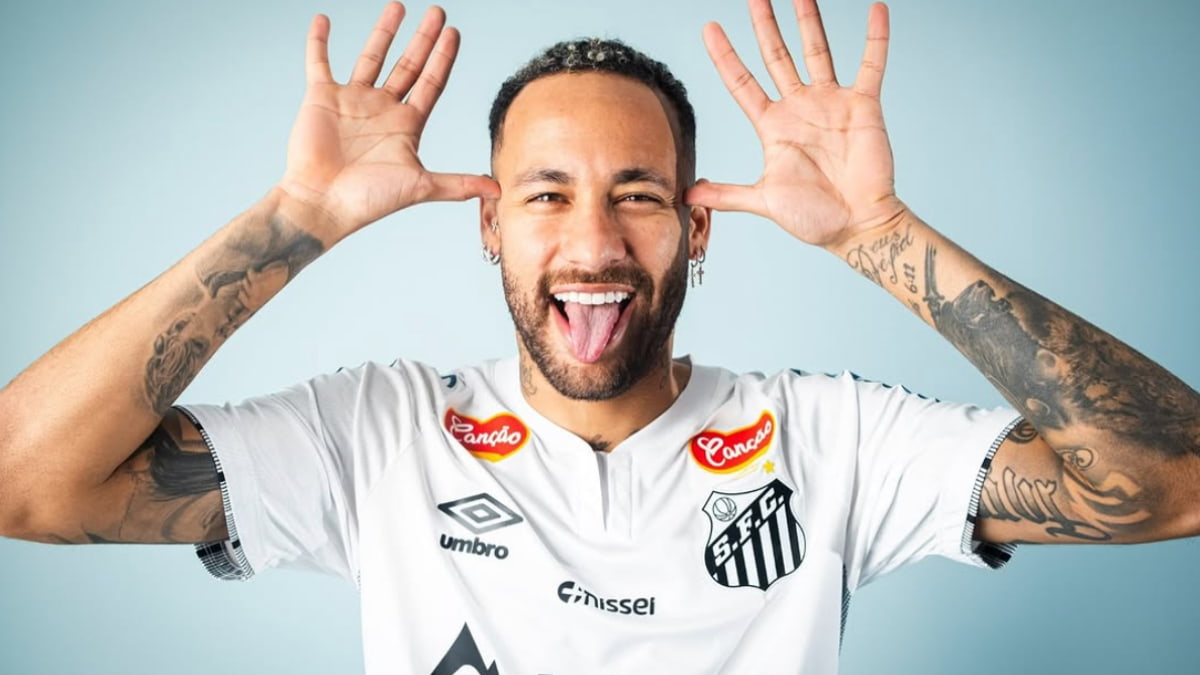 Neymar sorrindo e fazendo careta com a língua para fora, vestindo a camisa do Santos. Especula-se sua possível compra do clube.
