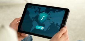 A imagem mostra uma pessoa segurando um tablet com a imagem de uma VPN conectada.