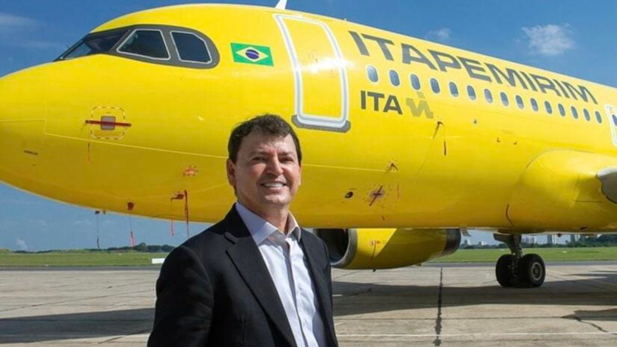 Sidnei Piva, então CEO do Grupo Itapemirim, sorrindo em frente a um avião amarelo da Itapemirim Transportes Aéreos, em um aeroporto.