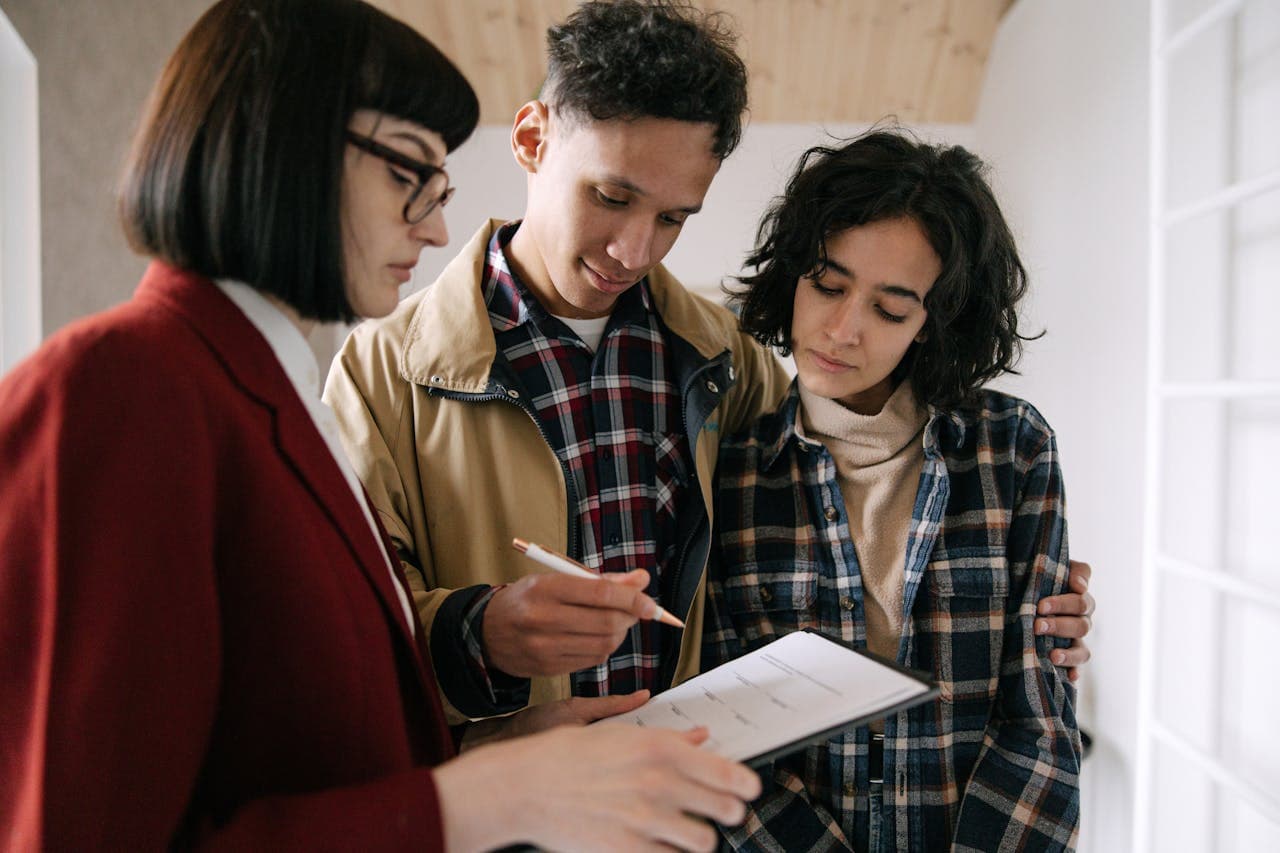 Jovem casal analisando contrato de financiamento imobiliário com corretora de imóveis, representando a compra da casa própria no Brasil.