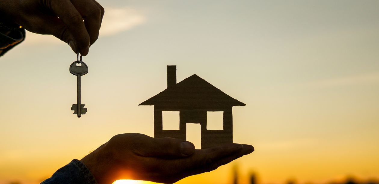 A imagem mostra uma pessoa segurando em uma mão uma miniatura de casa e uma chave na outra mão para representar que as ações EZETC3 valorizam.