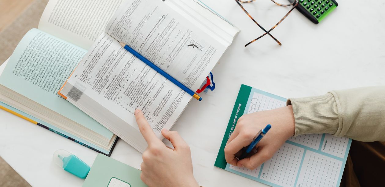 A imagem mostra uma pessoa sentada à mesa com cadernos e papéis para representar que as ações do setor da educação dispararem.