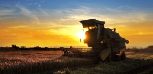 A imagem mostra uma máquina agrícola em uma lavoura para representar o agronegócio.