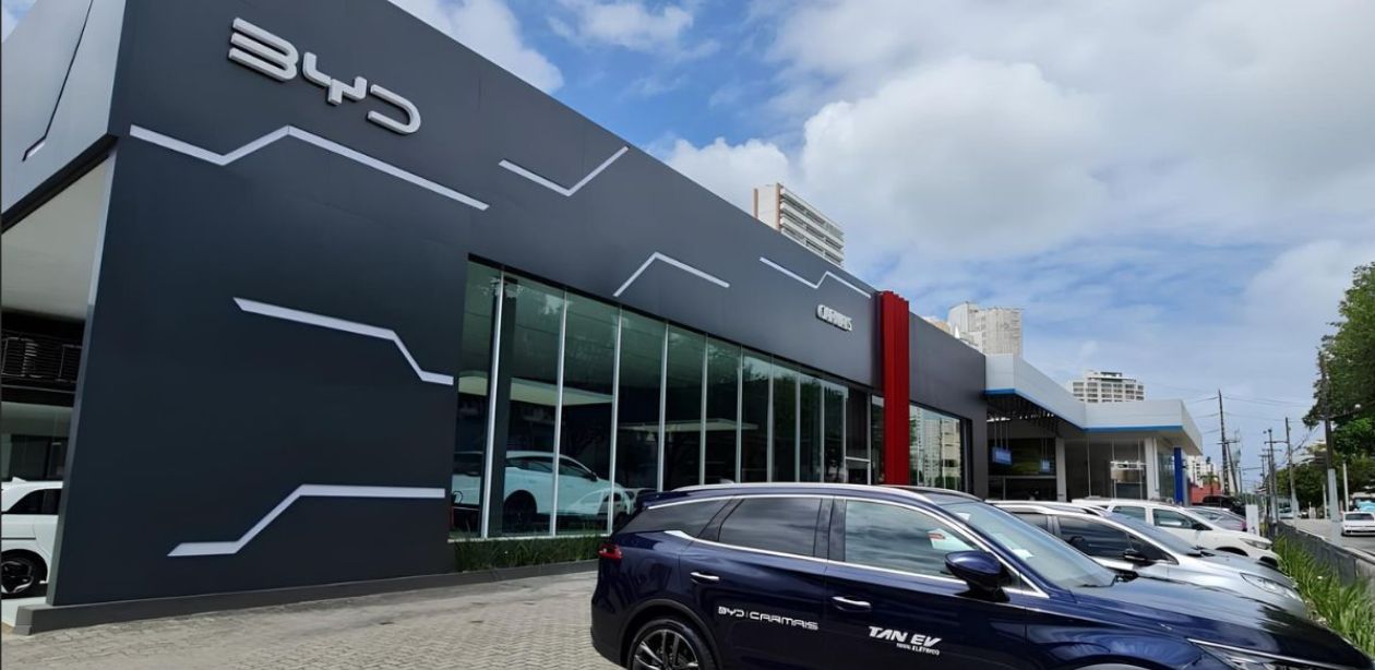 A imagem mostra a fachada de uma das unidades da BYD para representar que a BYD supera Tesla.
