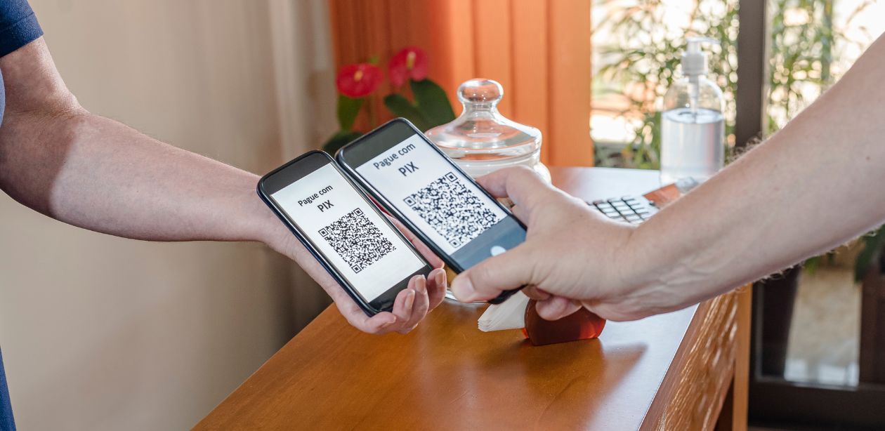 A imagem mostra duas pessoas aproximando seus celulares para fazerem uma transação via pix, para representar que os bancos vão excluir chaves pix.