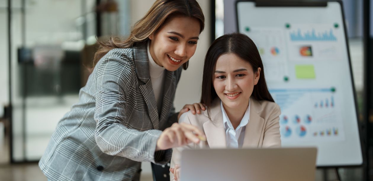 A imagem mostra duas mulheres na frente de um notebook para representar o consultor financeiro.