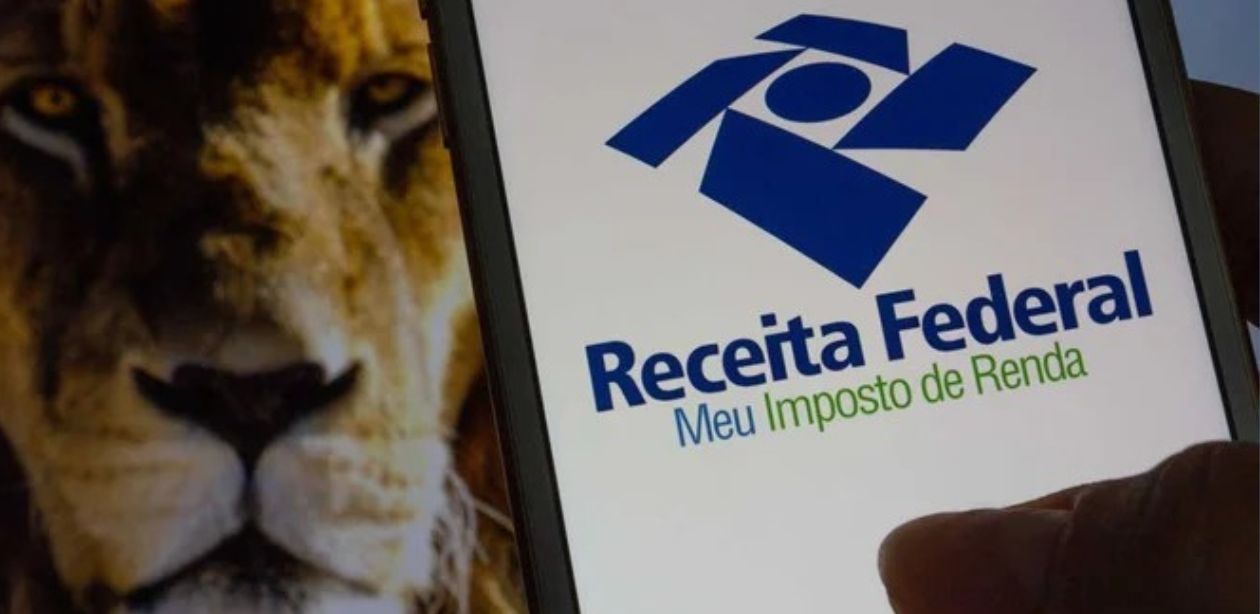 A imagem mostra um celular com a tela inicial do app Meu Imposto de Renda e ao fundo um leão para representar a declaração de imposto de renda 2025.