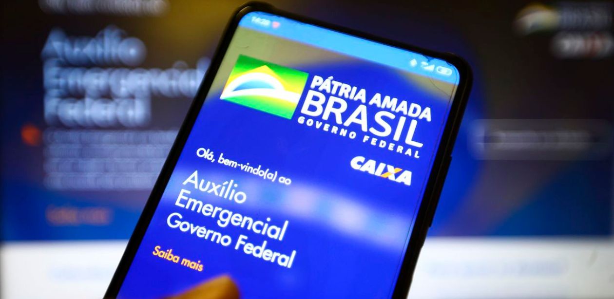 A imagem mostra um celular com o app do Auxílio Emergencial para representar a devolução do Auxílio Emergencial.
