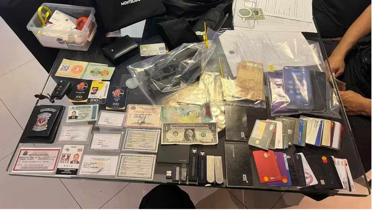 Materiais apreendidos durante investigação sobre fintechs e lavagem de dinheiro ligadas ao PCC, incluindo cartões, documentos e criptomoedas.