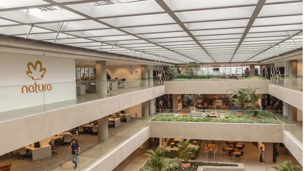 Interior da sede da Natura &Co com espaços abertos e vegetação, refletindo a estratégia de sustentabilidade e inovação da companhia.