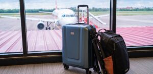 A imagem mostra uma mala de 10kg e 1 mochila em um aeroporto, no fundo aparece uma aeronave para mostrar as novas regras de bagagem da ANAC em 2025.