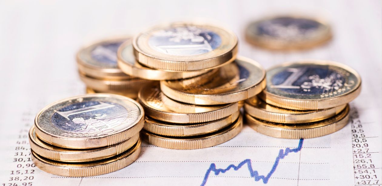 A imagem mostra moedas em cima de um papel e um gráfico subindo para representar que o PIB do Brasil cresce e impulsiona retomada econômica em 2025.