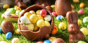 A imagem mostra diversos ovos de Páscoa e coelhos de chocolate em uma bola de chocolate.