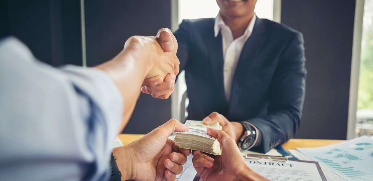 A imagem mostra um homem fazendo um pagamento para duas pessoas para representar o pagamento dos precatórios.