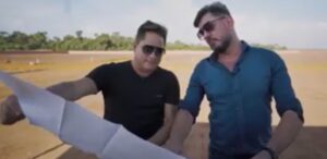 A imagem mostra o cantor Leornardo e o empresário Aguinaldo José Anacleto, dono da AGX Smart Life segurando um papel.