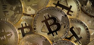 A imagem mostra várias moedas de Bitcoin para representar a queda do Bitcoin.