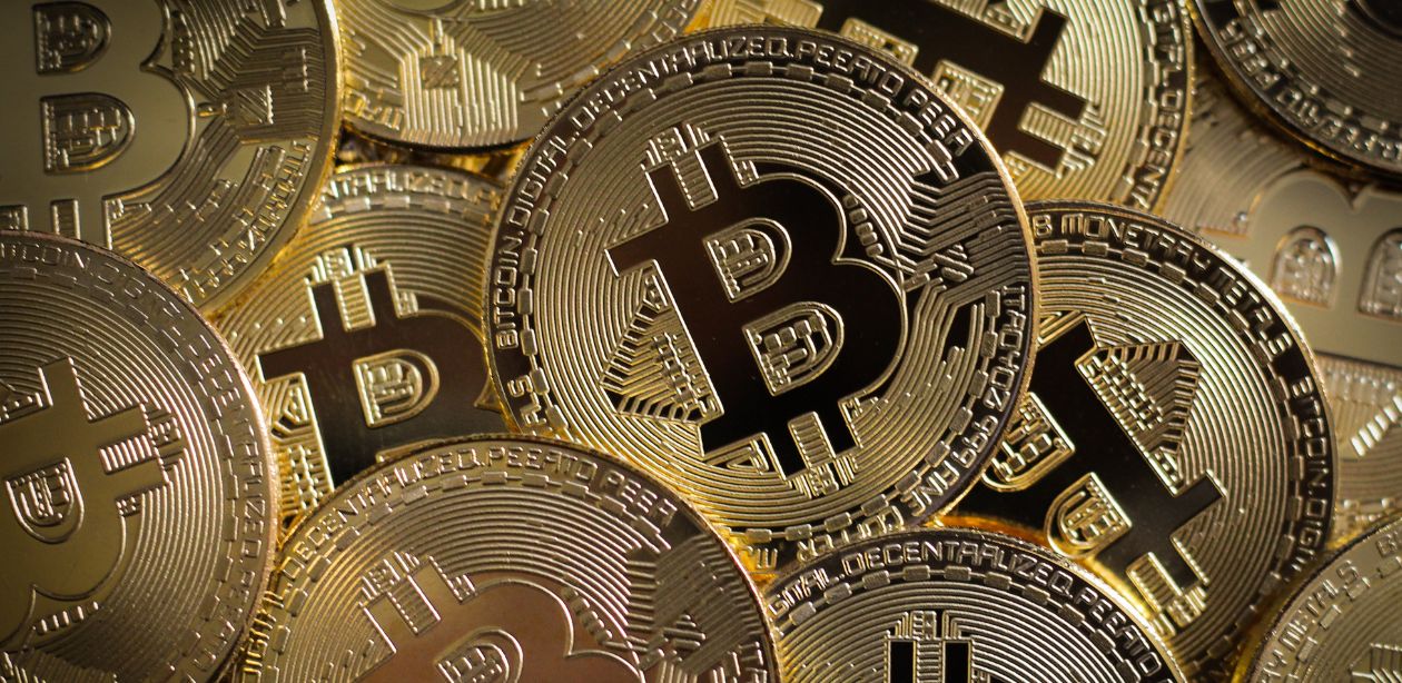A imagem mostra diversas moedas de Bitcoin para representar a queda do Bitcoin.