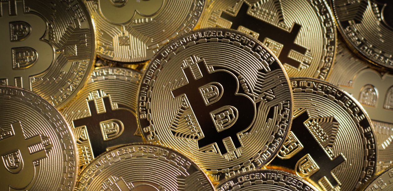 A imagem mostra várias moedas de Bitcoin para representar a queda do Bitcoin.