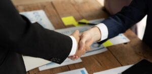 A imagem mostra dois homens apertando as mãos e fechando negócio para representar que a Shinagawa compra Reframax.