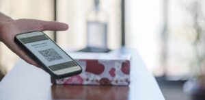 A imagem mostra uma pessoa segurando um celular com um qr code de pagamento via pix na tela para representar o vazamento de dados do pix.