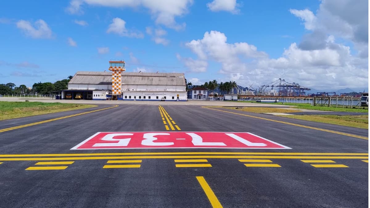 Aeroporto de Guarujá com pista reformada e torre de controle ao fundo, após investimentos do Novo PAC em infraestrutura aeroportuária.
