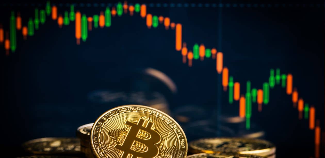 A imagem mostra um gráfico e moedas de Bitcoin.