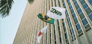 A imagem mostra um prédio da CMIG4 com as bandeiras da Cemig, Minas Gerais e Brasil para representar a Cemig em queda.