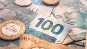 Carteira de PPPs dos estados ilustrada com cédulas de 100 reais e moedas do real brasileiro.