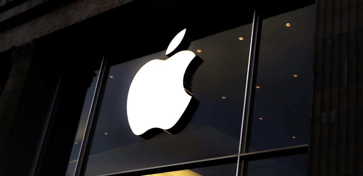 Logo da Apple iluminado na fachada de uma loja.