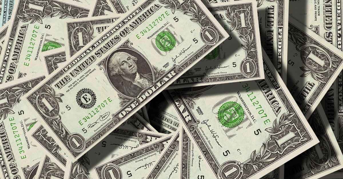 A imagem mostra notas de dólares para representar o mercado financeiro