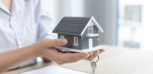 A imagem mostra uma pessoa segurando uma miniatura de casa e chaves para representar que o programa Minha Casa Minha Vida Faixa 4 impulsiona mercado imobiliário.