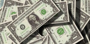 A imagem mostra notas de dólares para representar que a Selic pode não atingir 15% após tarifaço e dólar em queda.