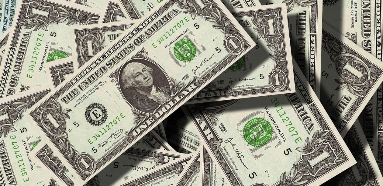 A imagem mostra notas de dólares para representar que a Selic pode não atingir 15% após tarifaço e dólar em queda.